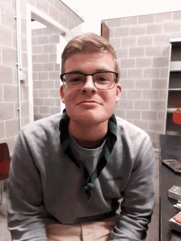a young man wearing glasses and a sweater that says ' scout ' on it