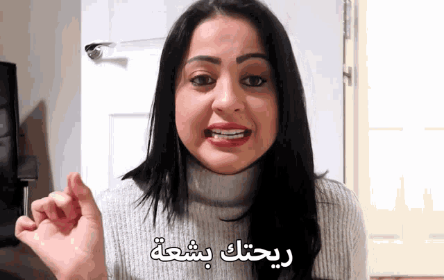 a woman wearing a turtleneck sweater is talking in a foreign language