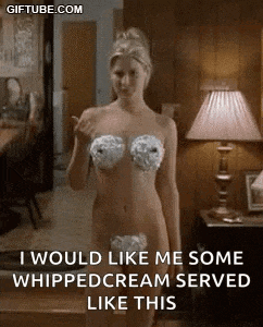 a naked woman with whipped cream on her breasts is standing in front of a lamp .