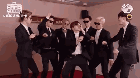 a group of men in suits and sunglasses are dancing in a room with the words hard carry on the wall behind them