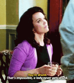 a woman in a purple sweater is holding a glass of wine and talking to a man .