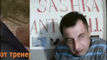 a man is sitting in front of a sign that says sashka ant all