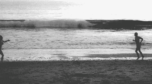 a man and a woman are running on the beach .