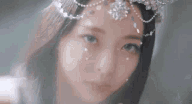 a close up of a woman wearing a crown on her head and looking at the camera .