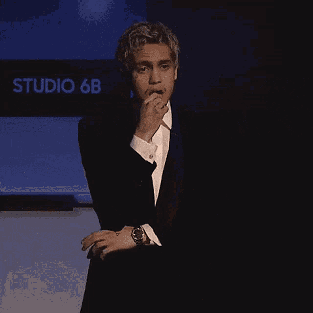 a man in a suit and tie is standing in front of a sign that says studio 6b