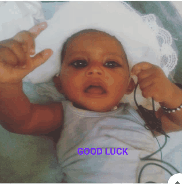 a baby is laying on a bed with the words good luck below him