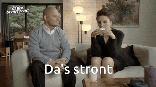 a man and a woman sit on a couch with da 's stront written in white letters