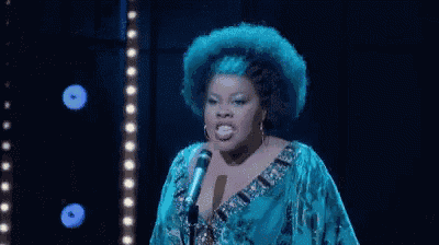 a woman in a blue dress is singing into a microphone .