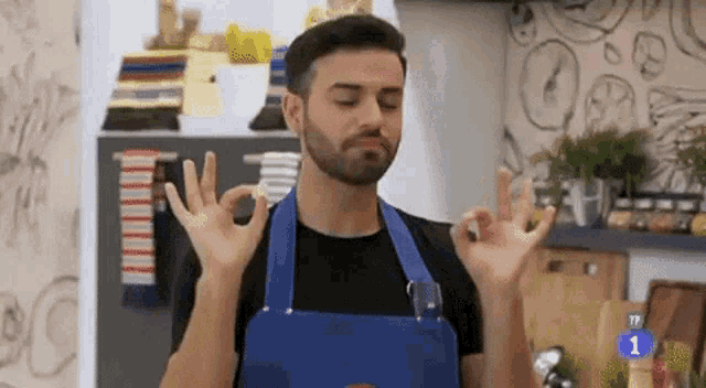a man in an apron is making an ok sign with his hands .