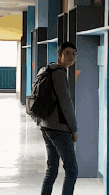 a man walking down a hallway with a backpack
