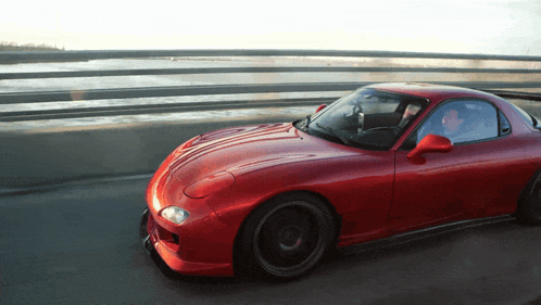 a red sports car is driving on a highway
