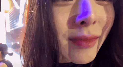 a close up of a woman 's face with a purple light in the background
