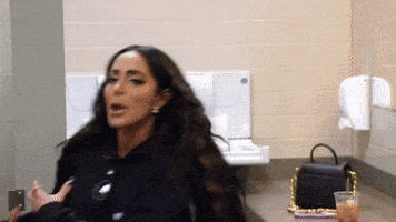 a woman with long hair is sitting in a bathroom next to a purse