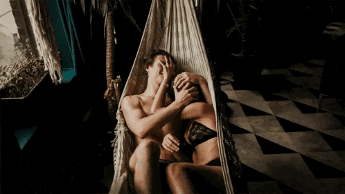 a man and a woman laying in a hammock