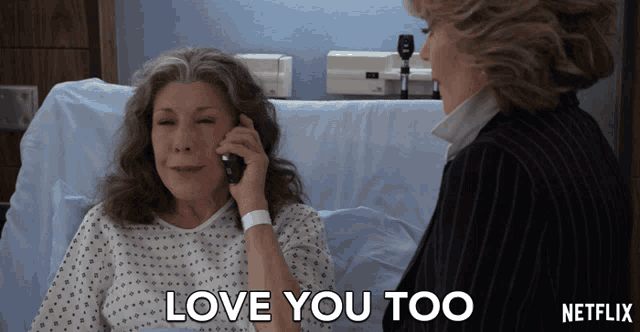 a woman in a hospital bed talking on a cell phone with the words love you too written on the bottom