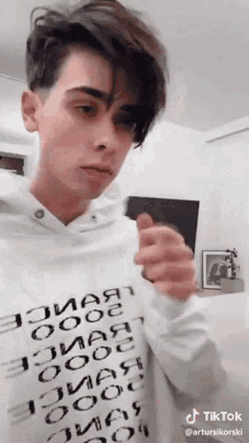 a young man wearing a white hoodie with russian writing on it