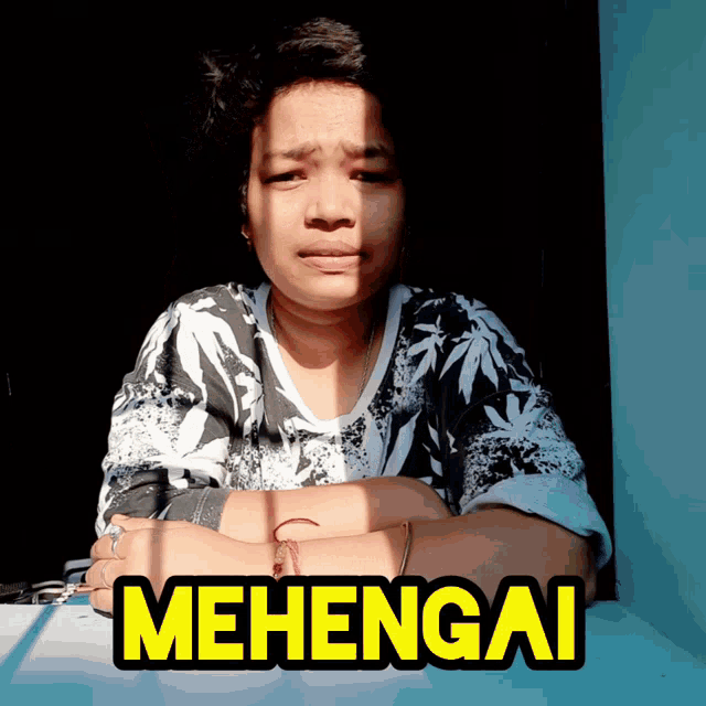 a woman is sitting at a table with the word mehengai on it