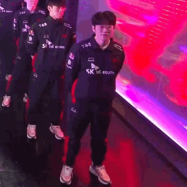 a man in a sk telecom uniform is standing in a line with other people .