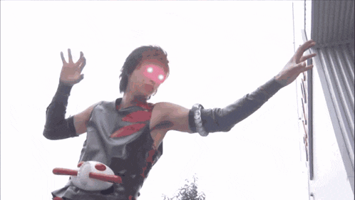a man in a costume with a red eye is standing in front of a building with his arms outstretched