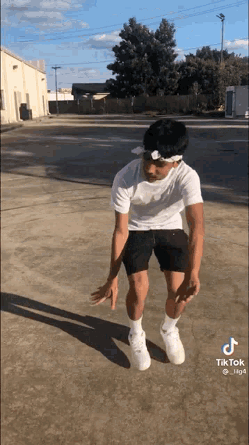 a man in a white shirt and black shorts is doing a trick on a concrete surface .