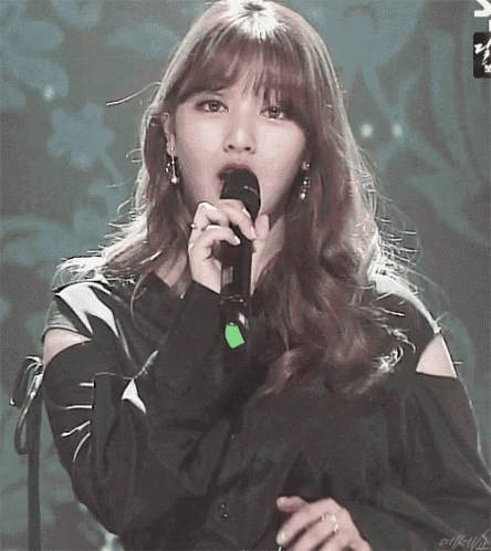 a woman is singing into a microphone on stage .
