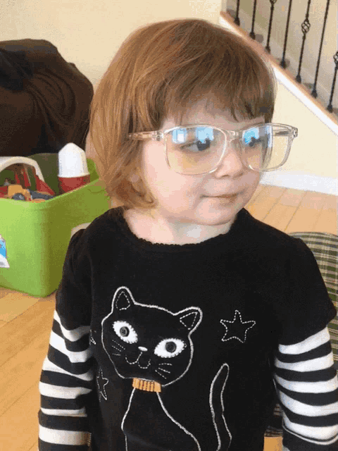 a little girl wearing glasses and a black shirt with a black cat on it