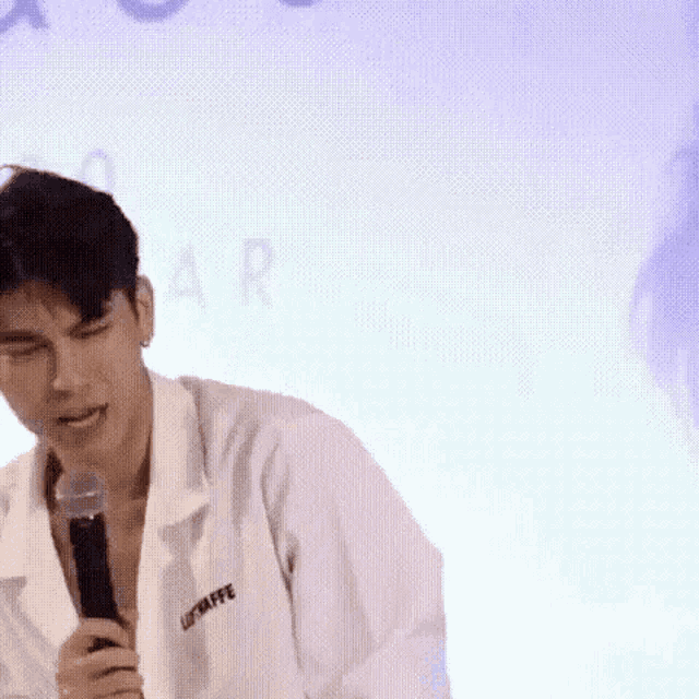 a man in a white coat is holding a microphone and talking into it .