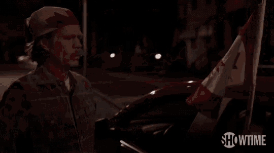 a car with a canadian flag on top of it is parked on the side of the road at night