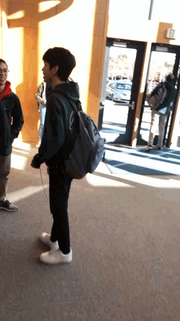 a man with a backpack is standing in front of a door that has the word exit on it