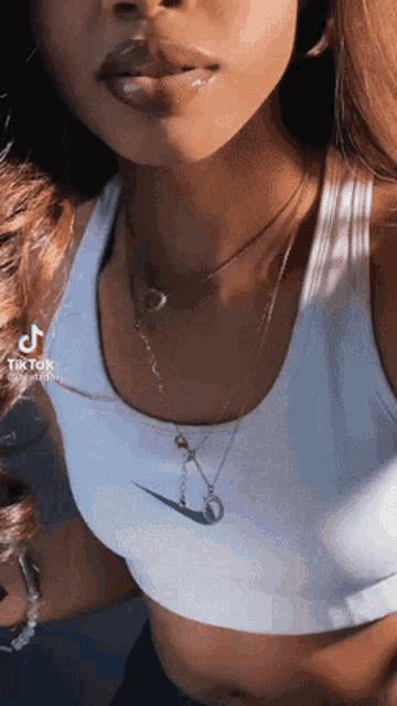 a woman wearing a crop top and a necklace with a nike logo on it