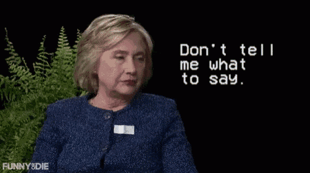 a woman in a blue jacket is sitting in front of a screen that says " don 't tell me what to say "