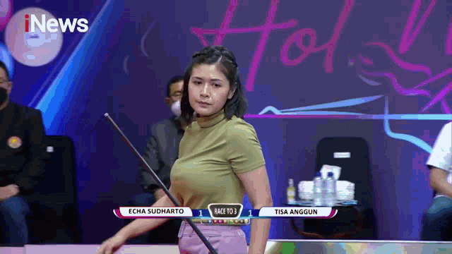 a woman is holding a pool cue in front of a screen that says i news
