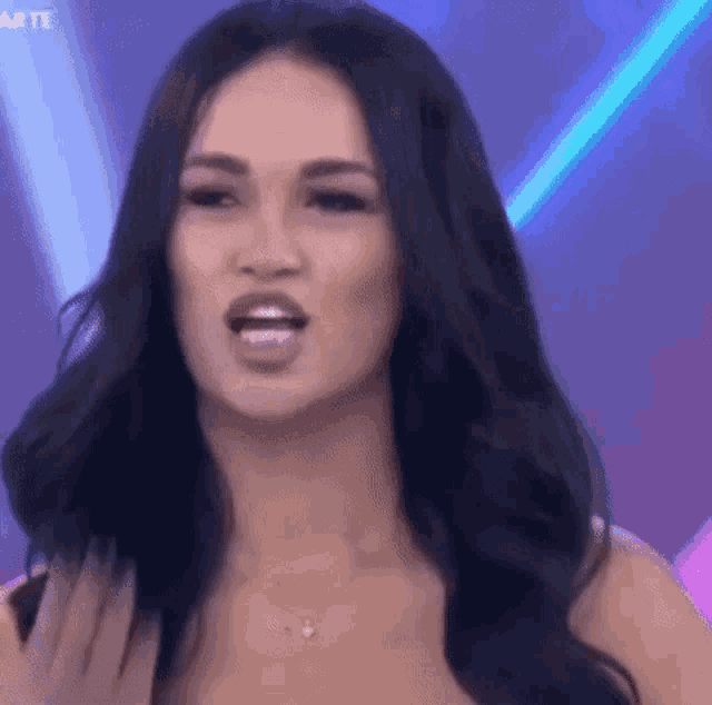 a woman with long black hair is making a funny face while standing in front of a stage .