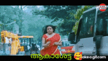 a woman in a red saree is walking down a street in front of a bus