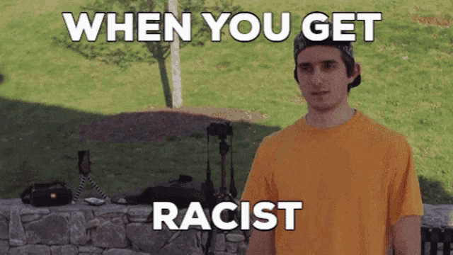 a man in a yellow shirt stands in front of a stone wall with the words when you get racist on the bottom