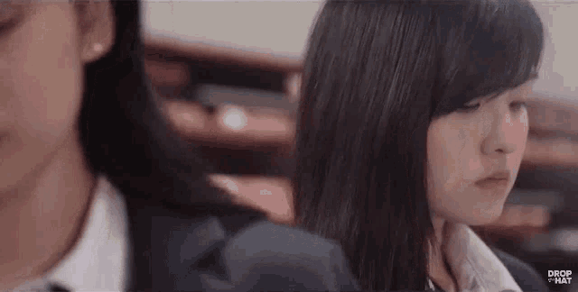 two girls are sitting next to each other in a classroom and looking at something .