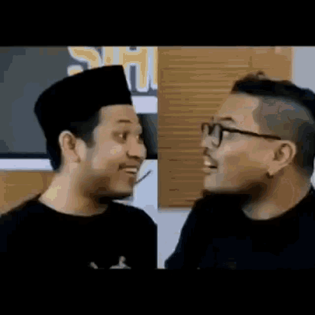 two men are standing next to each other and talking to each other .
