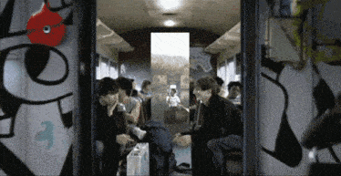 a group of people are sitting on a train with graffiti on the wall including the number 3