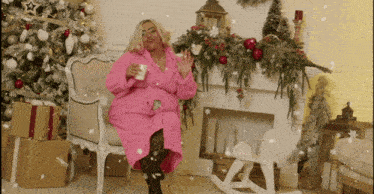 a woman in a pink robe sits in front of a fireplace