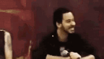 a man with a beard is smiling and looking at the camera in a blurry photo .
