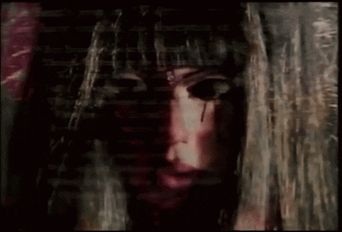 a close up of a woman 's face with blood dripping from her eyes and nails .