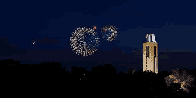 fireworks are displayed in the night sky above a tower