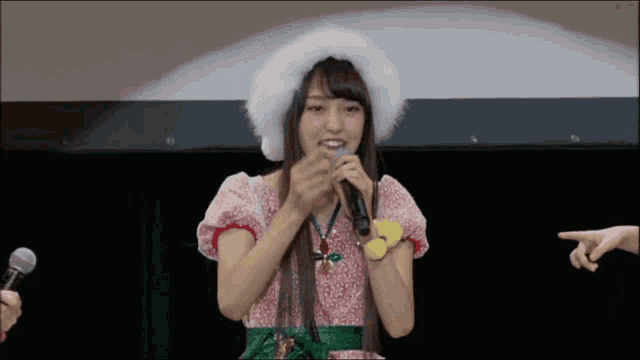 a woman wearing a santa hat holds a microphone in her hand