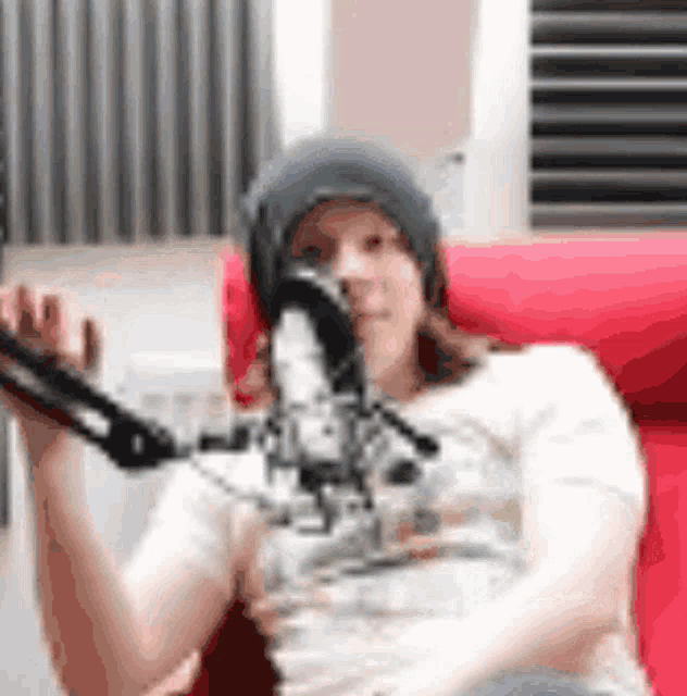 a woman in a beanie is sitting in front of a microphone