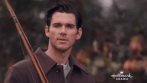 a man in a trench coat is holding a rifle in his hand .