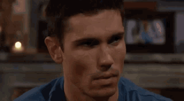 a close up of a man 's face in a blue shirt looking at the camera .