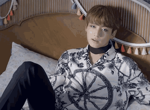 a young man is laying on a bed wearing a floral shirt