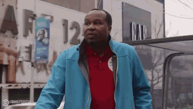 a man wearing a blue jacket and a red shirt is standing in front of a gap store .