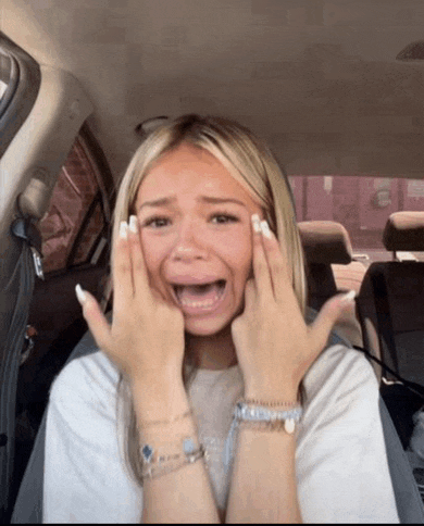 a woman in a car with her hands on her face