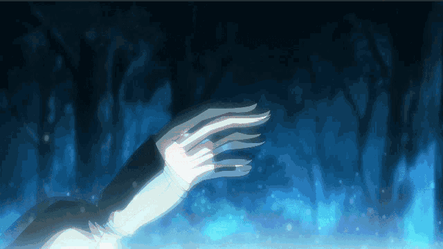 a person 's hand is reaching out towards a forest